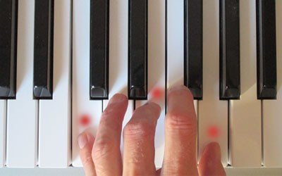 picture of hand playing a chord on piano