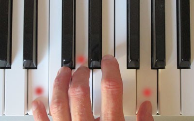 picture of hand playing a chord on piano